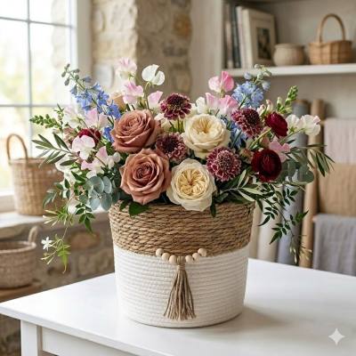 مزهرية زخرفية مصنوعة يدوياً من الخيزران وحبل القطن، مزينة بشرابة وخرز.